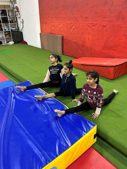 Even during a break, the dedication shows. Young gymnasts practicing their splits on the mats, making flexibility a natural part of their time at the academy.