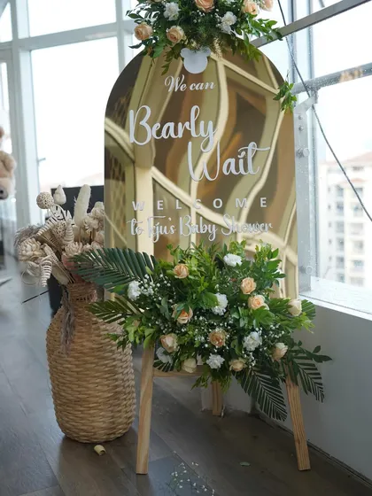 A chic welcome sign for a 'Bearly Wait' baby shower. The mirrored acrylic sign is paired with dried pampas grass and fresh flowers for a perfect boho-modern look.