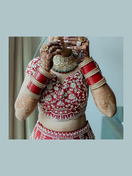 A creative shot of the bride's hands, adorned with henna and chooda, held up to her face. This photo highlights the important details of her bridal look.