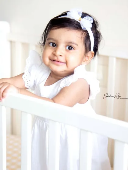 Snuggled up and safe in her crib. A simple, classic portrait in a white dress is a timeless way to capture your baby's sweetness.