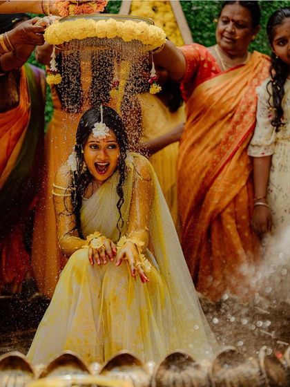 Capturing the pure, unscripted joy of a Haldi ceremony. The background shows our dense floral wall that adds to the celebratory feel of the event.
