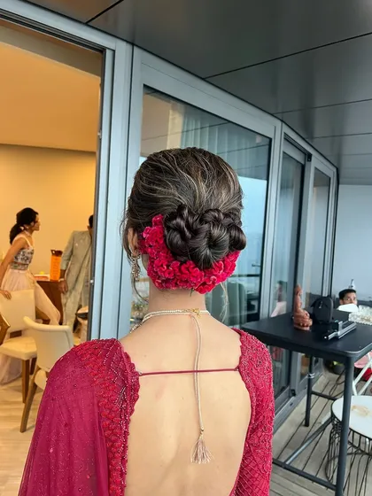 A beautiful and intricate knotted bun wrapped in fresh red flowers, creating a bold and romantic statement for a bride on her wedding day.