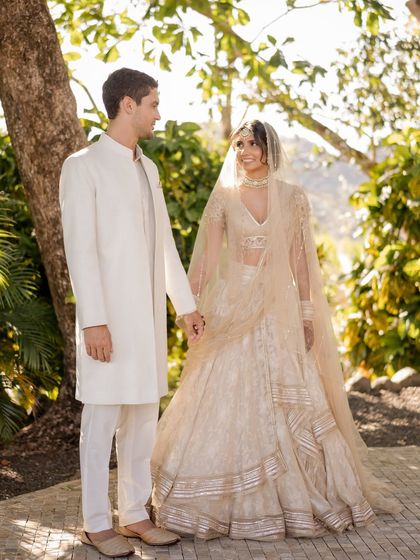 A clean and classic look for a minimalist beach wedding. This couple wanted elegance and simplicity. The bride wears a lightweight Tarun Tahiliani lehenga, and the groom is in a custom-made white sherwani, perfect for the serene setting.