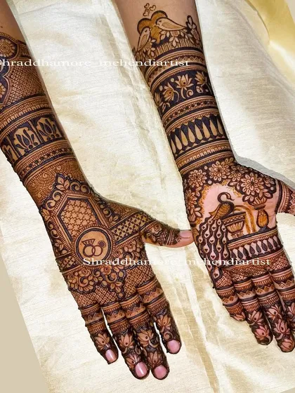 A classic engagement design with interlocking rings on one palm and a peacock pouring water on the other. The arms feature love birds and lotus bands.