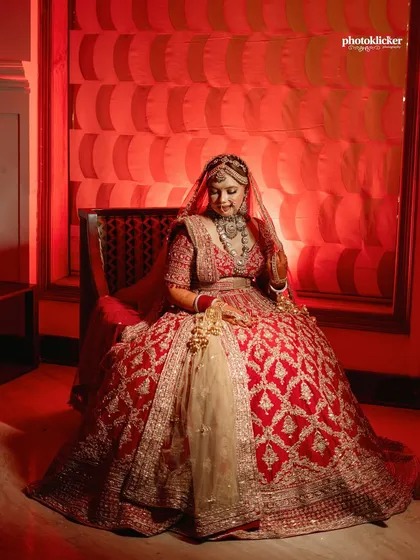 A regal bridal portrait, using dramatic red lighting to complement her lehenga and create a powerful, artistic image.