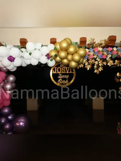 The entrance to this first birthday party sets a festive tone with a beautiful balloon and floral arch. A custom sign with the child's name welcomes guests to the celebration.