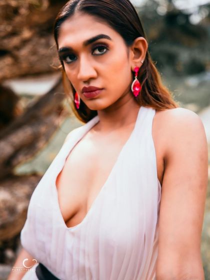 A captivating close-up that highlights her strong features and the bold pink earrings. Her gaze is intense and full of story.