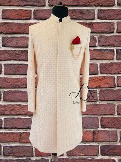 Tailored to fit you perfectly, this classic cream sherwani is the ultimate fashion statement. The textured fabric and simple brooch detail create a look of sophisticated simplicity.