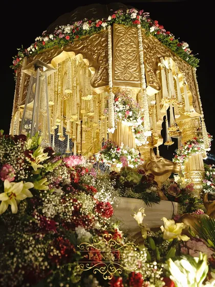 A closer look at the floral artistry surrounding the mandap. We use a mix of lush blooms like lilies and baby's breath to soften the majestic gold structure, creating a perfect balance of opulence and romance.