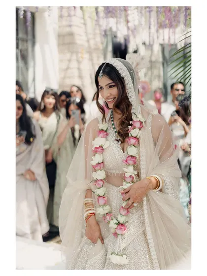 A happy, candid shot of the bride just after the Varmala ceremony. Her joyful smile and the crowd of loved ones in the background capture the celebratory atmosphere of the moment.