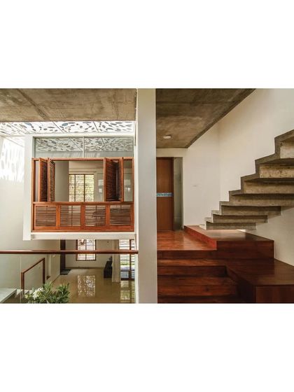 The floating concrete staircase and wooden bridge in the Cube Square residence create a sense of lightness and verticality within the home's central atrium.