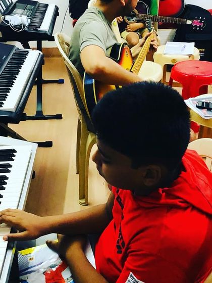 A student practices on his keyboard during a group session. The class includes a mix of instruments, allowing students to learn how to play in an ensemble.