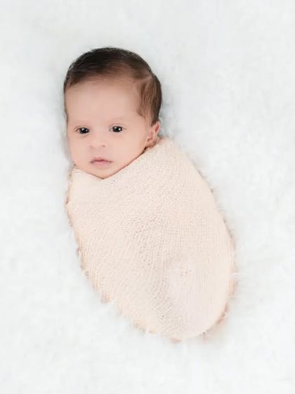 A precious newborn, swaddled and awake, looking curiously at the world. Capturing these early moments of awareness is just as special as the sleepy ones.