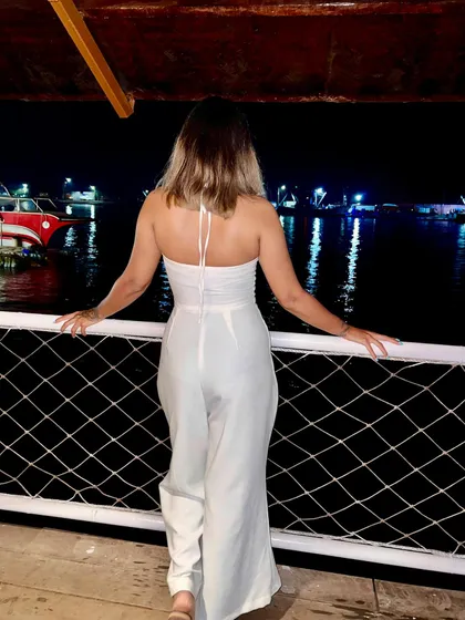 Enjoying the view from a boat in Goa. I'm wearing a white halter-neck jumpsuit, a perfect, breezy outfit for a vacation evening.