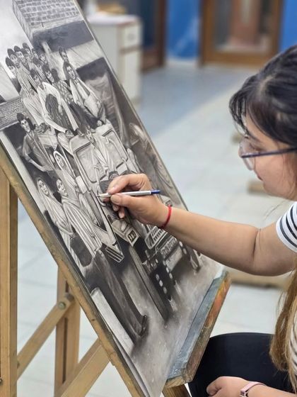 A side view of the artist at work, showcasing the techniques used to shade and define the figures and the vehicle in her charcoal composition.