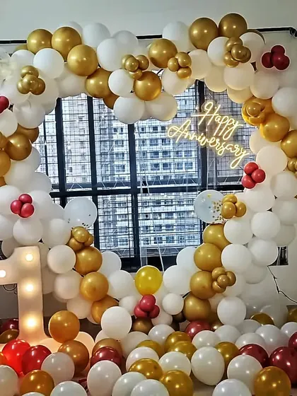 A heart-shaped balloon frame for a first anniversary celebration. This white and gold setup includes a 'Happy Anniversary' neon sign and a light-up number '1'.