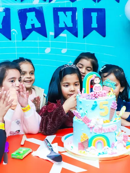 The birthday girl surrounded by friends, ready to cut her amazing rainbow and ice cream themed cake. We coordinate the entire celebration for a seamless experience.