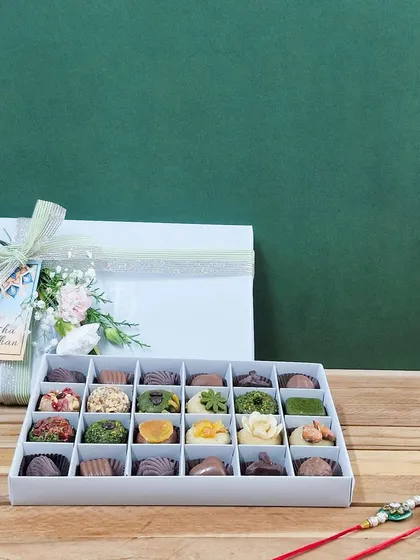 A beautifully composed shot of the 24-piece mixed collection, ready for gifting. The elegant box and festive accompaniments make it a memorable Rakhi present.