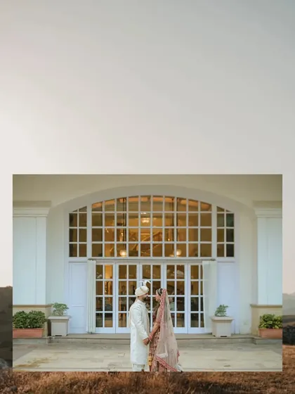 A minimalist yet grand composition. The couple stands before a large, white arched doorway, creating a sense of scale and elegance in this beautifully simple pre-wedding portrait.
