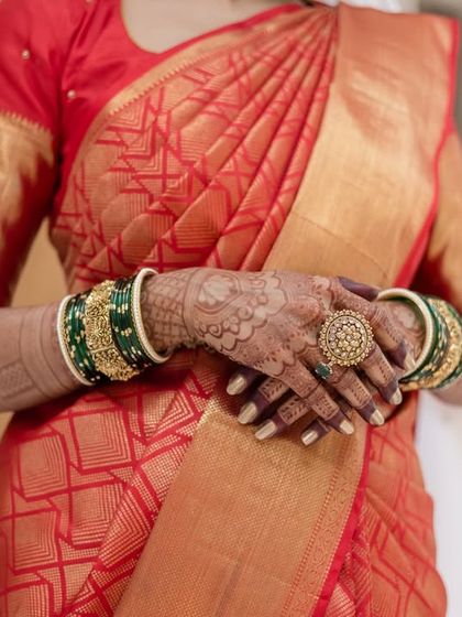A close-up of a bride's hands, adorned with henna and green bangles, held by her groom. A simple, beautiful shot symbolizing their union.