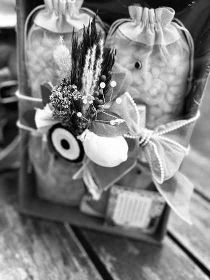 A black and white shot highlighting the textures and details of the Moroccan-themed hamper. The combination of dried florals, an evil eye charm, and a delicate bow creates a rich, layered look.