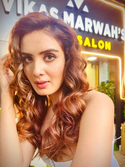 A client selfie outside the salon, showing off her new warm-toned highlights. The color looks fantastic in the golden hour light, proving that the right shade can make you glow.