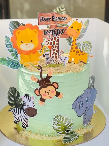 A delightful jungle-themed cake for a first birthday, featuring a lion, giraffe, and monkey.