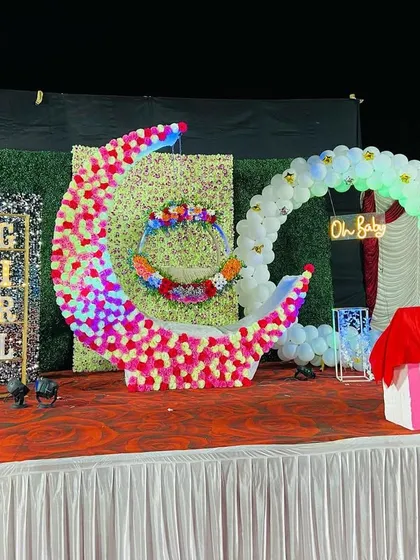 A beautiful naming ceremony stage featuring a large floral moon cradle and a circular balloon arch with an 'Oh Baby' sign.