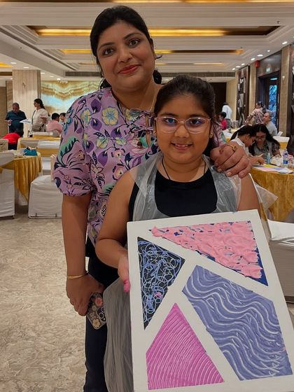 A mother and daughter proudly pose with the texture art piece they created together.
