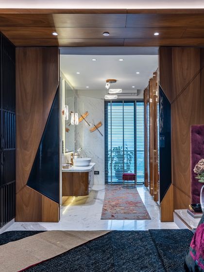 A view from the master bedroom in the Filigree House, looking towards the ensuite bathroom. The geometric sliding doors in wood and black add a modern, graphic element to the space.