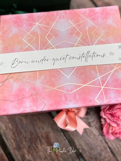 The story often begins with the box itself. This celestial-themed gift box was designed for a baby girl, with a custom sleeve that reads "Born under quiet constellations," setting a magical and personal tone before it's even opened.