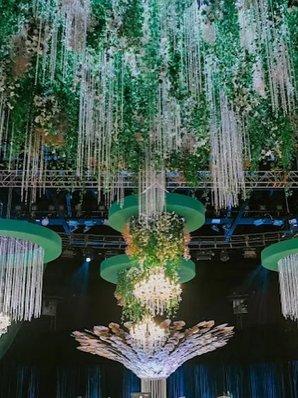 The central, sculptural tree installation is crowned with a massive chandelier, creating a stunning union of natural and man-made beauty that served as the heart of the venue.