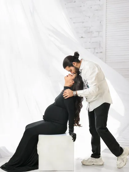 A tender kiss and a flowing white fabric create a dramatic and romantic scene. This style of couple's maternity photography is perfect for capturing passionate and artistic moments.