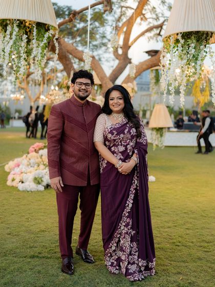 The couple's coordinated reception outfits in a rich aubergine and champagne palette, perfect for an elegant evening under the stars.