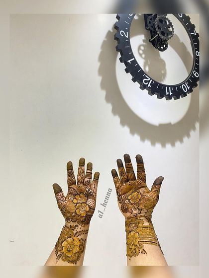 A creative shot of a floral henna design with a decorative clock in the background.
