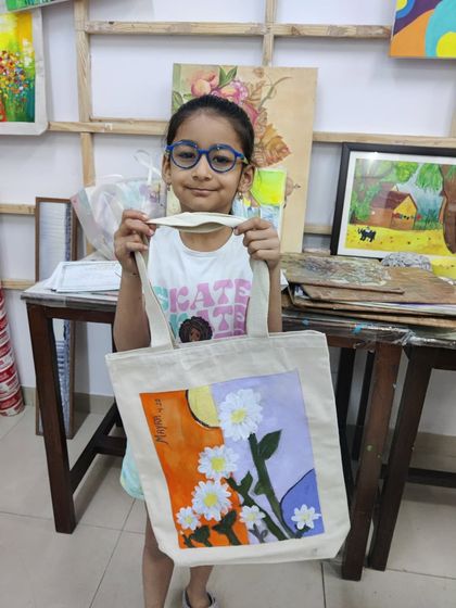 A smiling student with her hand-painted floral tote bag. These workshops are a fantastic way to combine creativity with a useful craft.