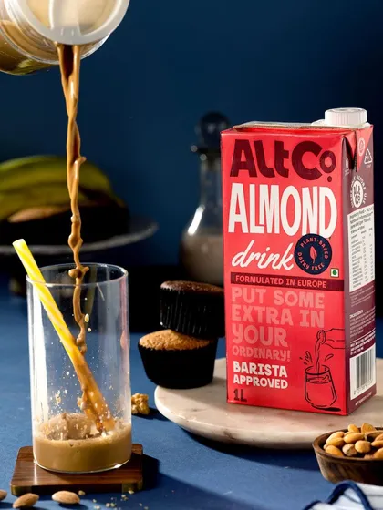A dynamic pour shot of Alt Co. Almond Drink. The frozen motion of the liquid creates a powerful sense of action and energy, making the product look delicious and exciting.
