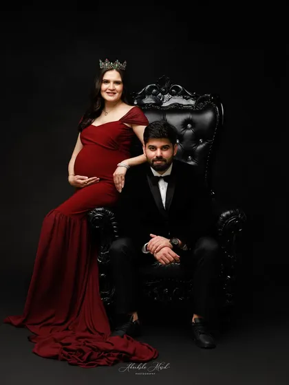 A royal-themed maternity portrait. The elegant throne and formal wear create a stunning, artistic image that celebrates the couple's journey.