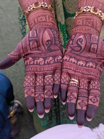 A close-up of the beautiful dark stain on a client's hands. The design with peacocks and elephants looks even more stunning with this rich color.