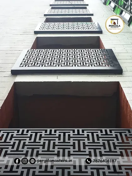 These laser-cut metal panels with a bold geometric pattern are used as window coverings or decorative facade elements. The view from below shows the repeating design, which adds a strong graphic quality to the building's exterior.