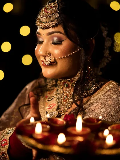 A serene moment captured during the Diwali shoot. The soft light from the diyas beautifully illuminates the student's makeup work.