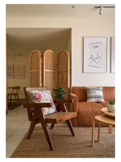 A closer look at the living space, focusing on the handcrafted wooden armchair with woven cane details. This piece exemplifies our commitment to bespoke solutions that blend traditional craftsmanship with modern comfort.
