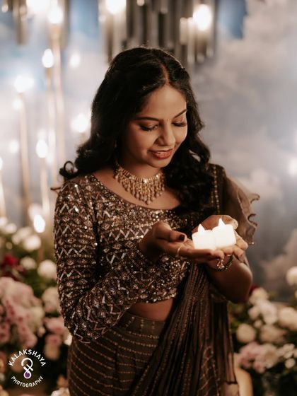 A close-up of the bride holding candles, her face lit with a gentle smile during her Mehendi ceremony.