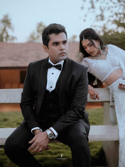 A candid shot of the couple at their outdoor reception, with the groom seated and the bride leaning in.