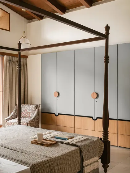 These bespoke wardrobes blend a soft, powdery grey with warm oak. The oversized circular wooden pulls act as modern Kolam-inspired strokes, adding a graphic and tactile detail to the minimalist design.