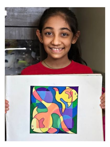 The smiling student holding her colourful fish design. Exam preparation can be a fun and creative process.