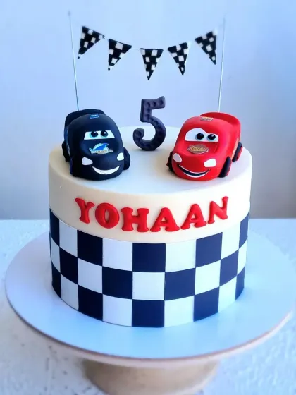 A closer view of the McQueen cake, focusing on the two hand-sculpted car toppers.