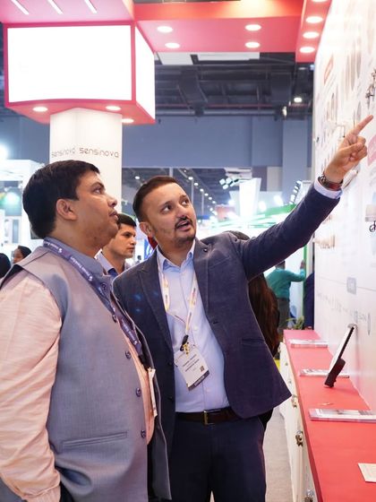 A moment of discovery as an exhibitor points out key details of a lighting solution to an engaged attendee.