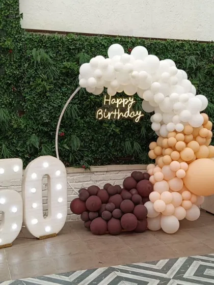 We create elegant setups for major life milestones, like this 50th birthday celebration. The design combines a modern balloon ring in a sophisticated color palette with large, illuminated marquee numbers and a custom neon sign for a personalized touch.