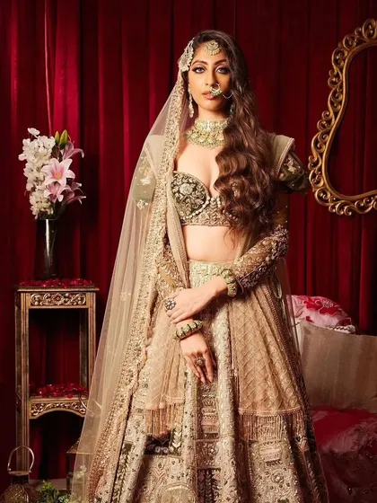 This modern bridal look features soft, romantic waves and a stunning lehenga. The makeup is glamorous yet understated, allowing the bride's natural beauty and the intricate outfit to take center stage.